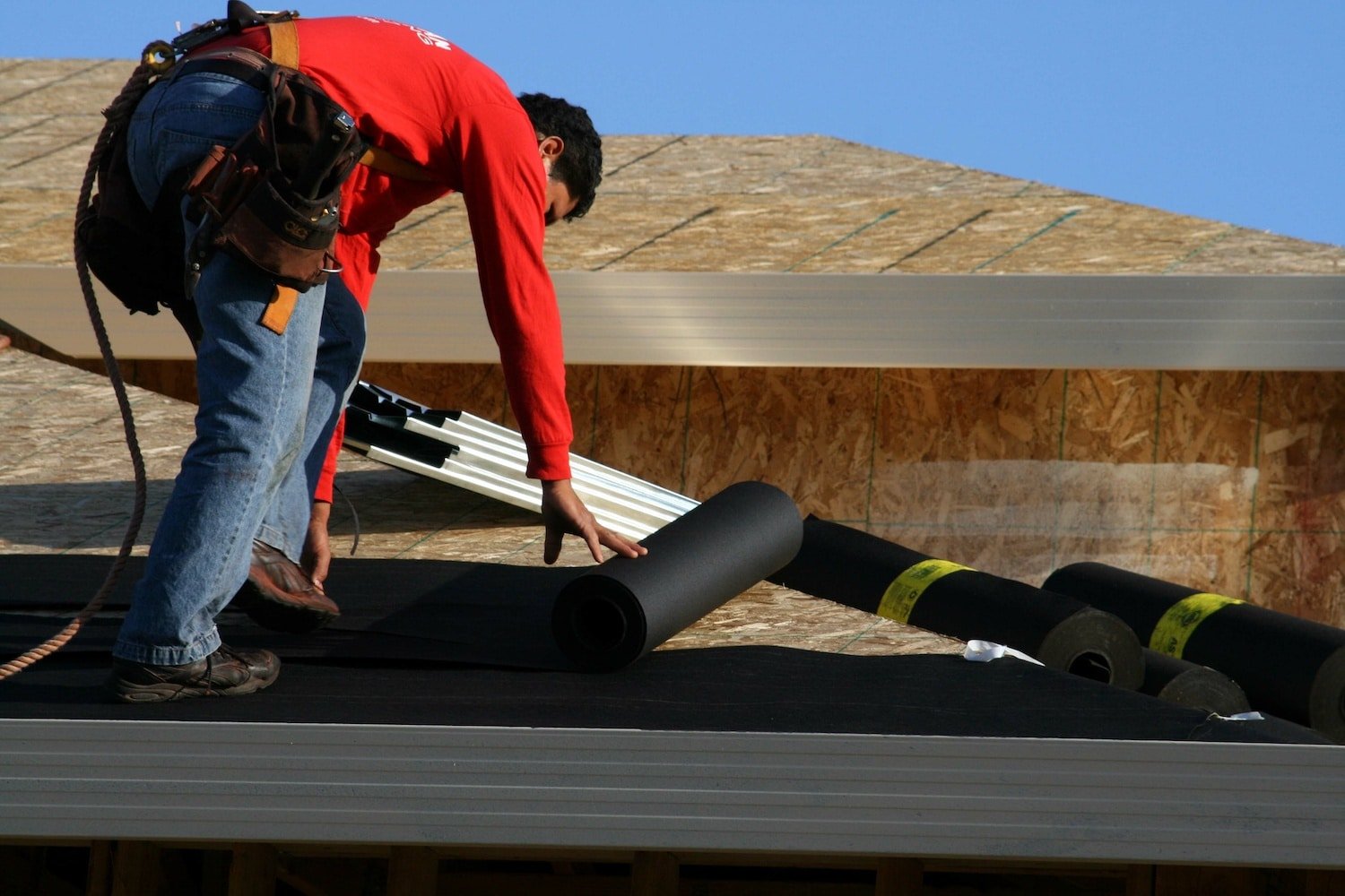 new roofing contractor installing underlayment on roof