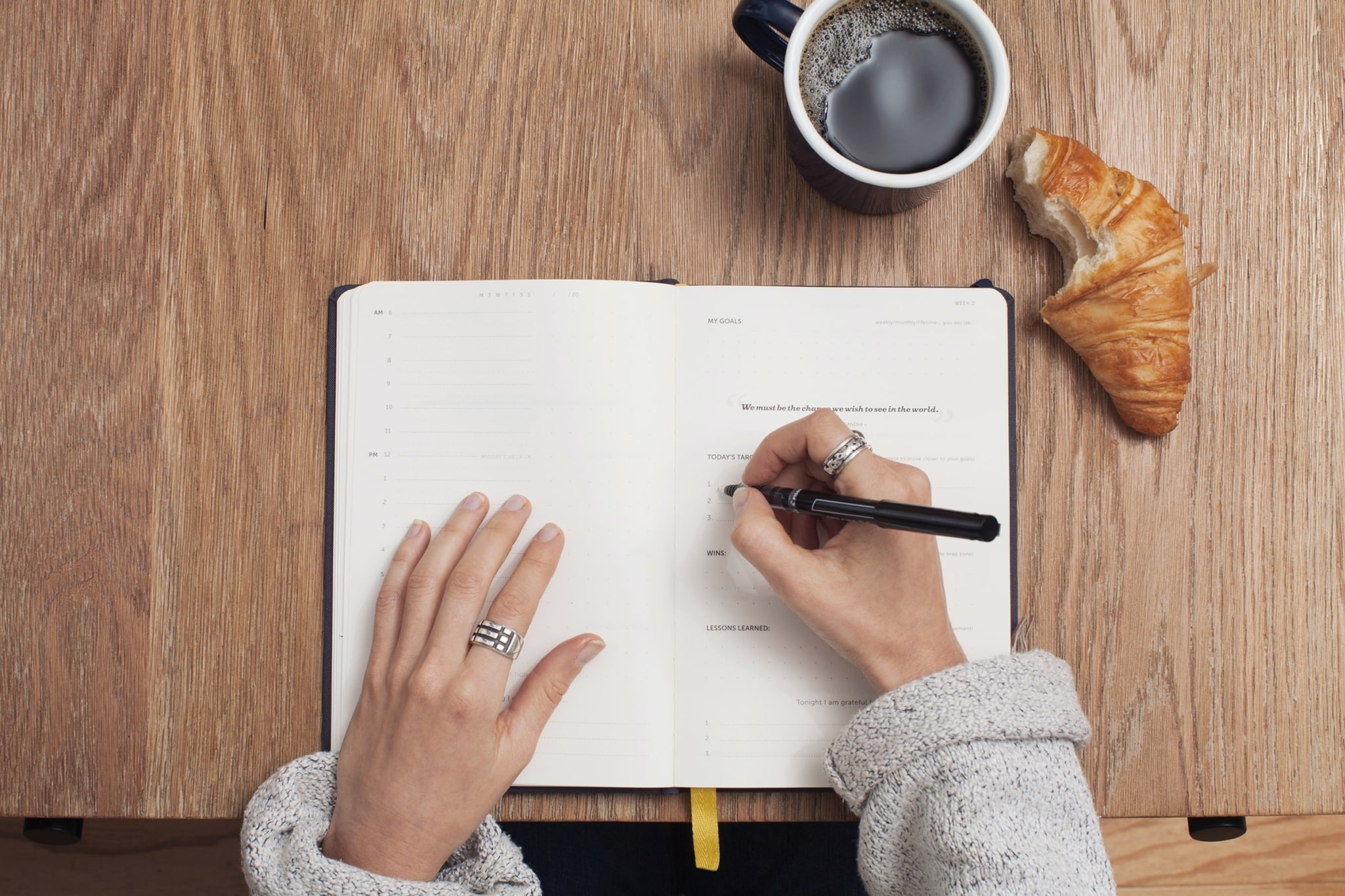 person sitting and writing with coffee and bread.