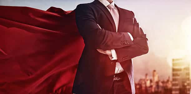 On Hook Agency's website, a confident figure in a suit stands with arms crossed and a flowing red cape, set against a sunlit cityscape. This image embodies the strength and ambition required to master client interactions for successful sales roleplay.