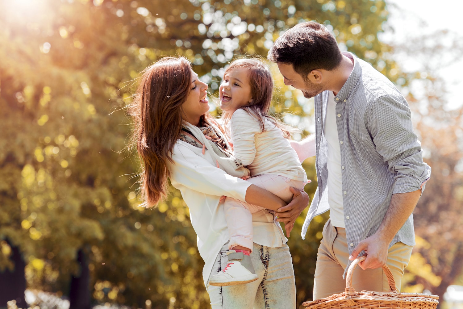 Mom, dad, and kid hugging, enjoying nature outside