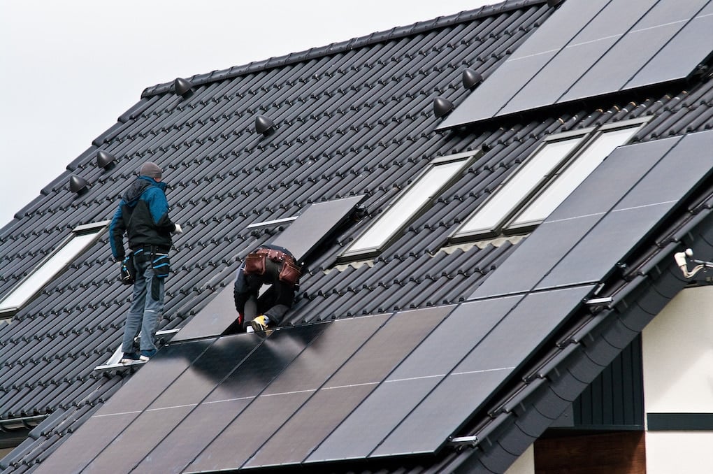 Men installing new solar panels on the roof of a private house.