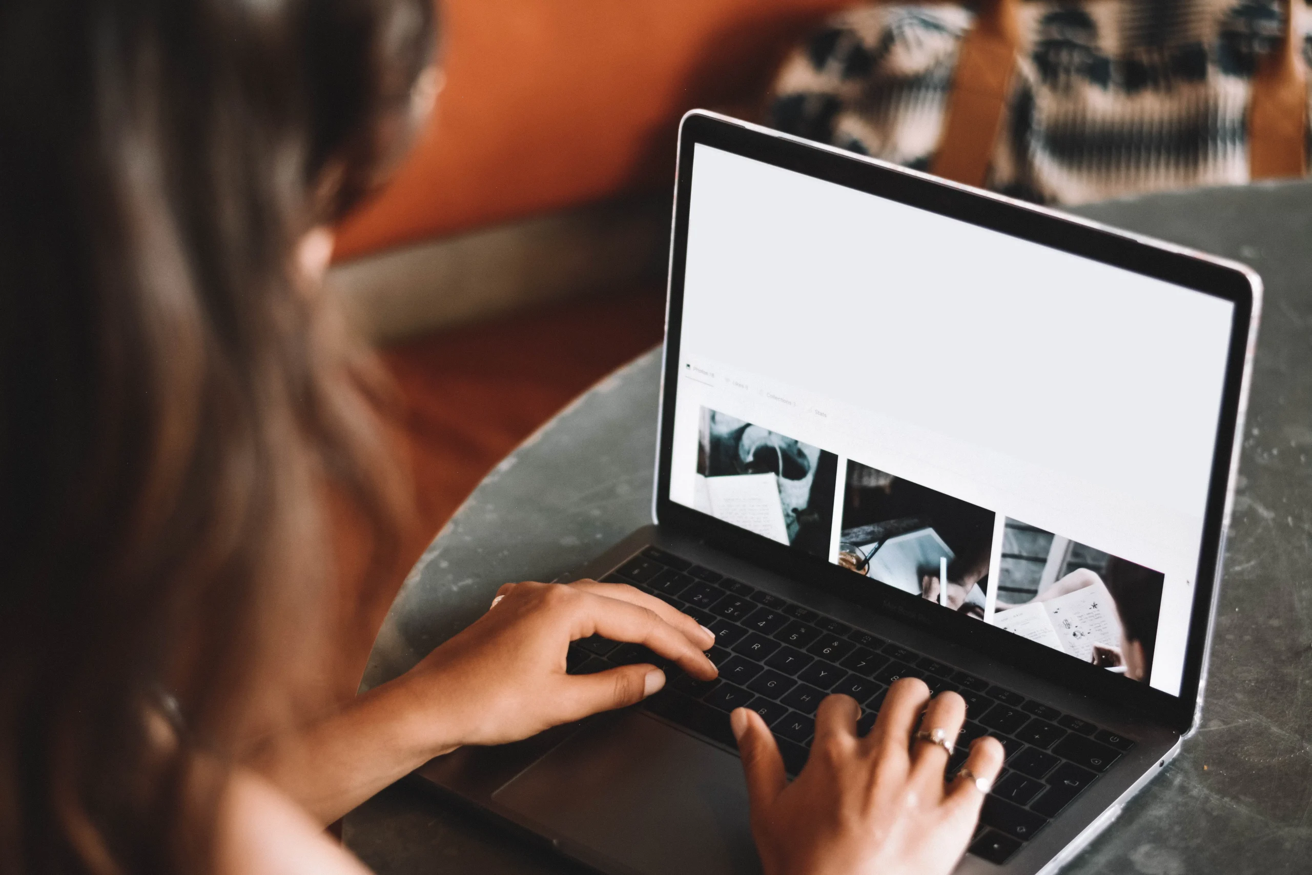 A focused individual types on a laptop, immersed in a San Jose web design project. A blurred screen showcases multiple images, while an indoor setting provides the backdrop.