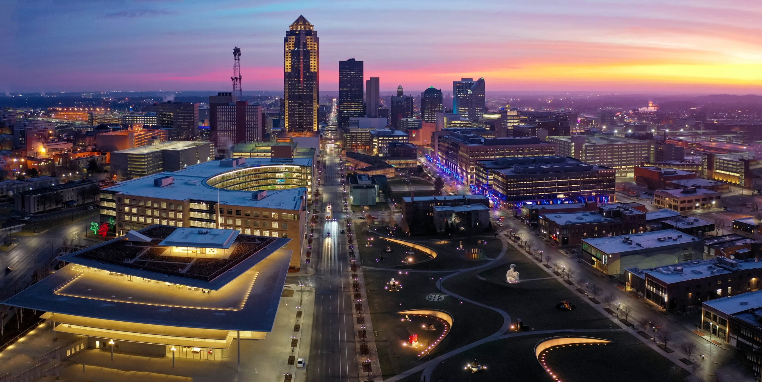 Discover Des Moines from above: a dynamic skyline at sunset, where modern skyscrapers meet bustling streets. The vibrant mix of illuminated buildings reflects the city’s growth and SEO potential. Explore how Hook Agency can elevate your business in this thriving urban landscape.