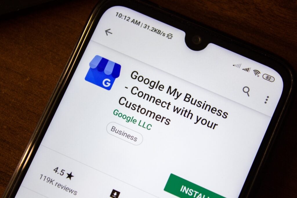 A smartphone screen displays the Google My Business app in the Google Play Store. The app, developed by Google LLC, features a blue storefront icon, boasts a 4.5-star rating from 119K reviews, and includes an install button.