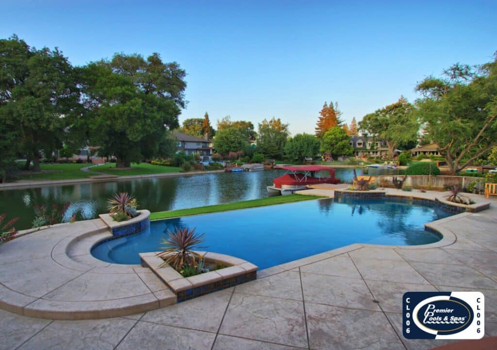Modern pool and spa by top installers, lakeside view with trees, homes, boats; Premier Pools & Spas logo in corner.