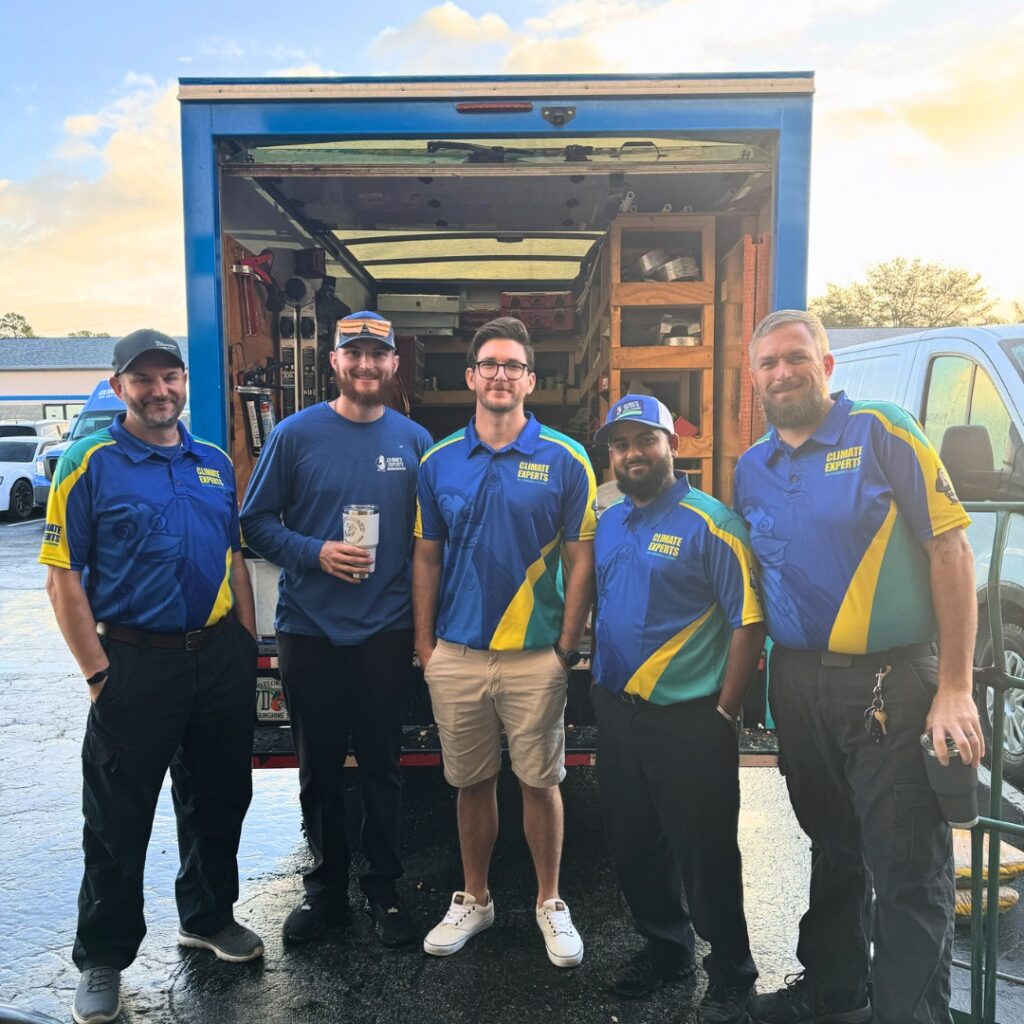 Five employees stand before an open, tool-filled van. Four wear Hook Agency client uniforms; one in blue shirt holds a cup.
