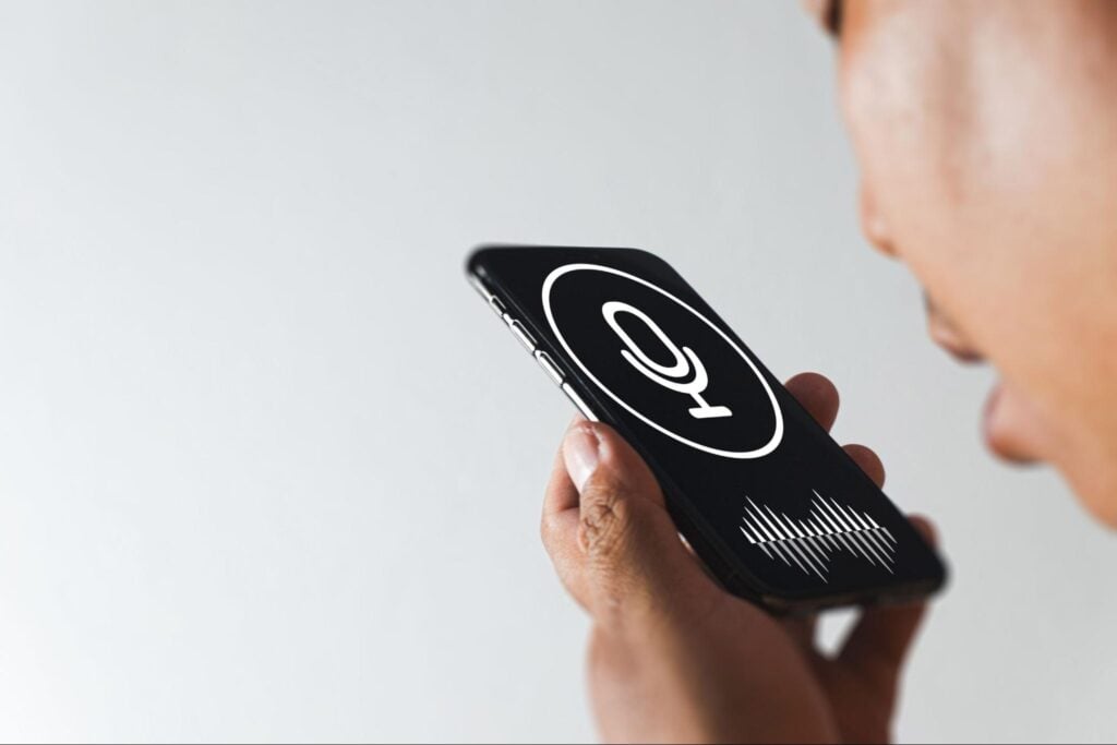 User speaks into a smartphone with a visible mic icon and audio waves—showing voice search for home service businesses.