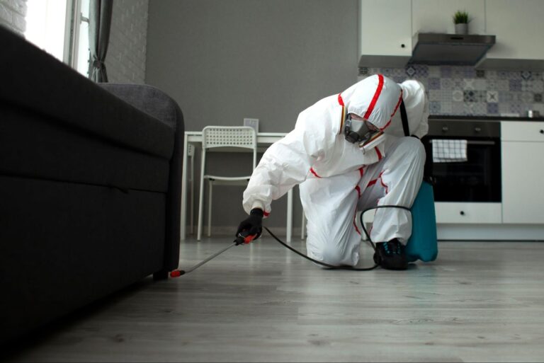 Professional in full protective gear disinfects a modern kitchen, demonstrating top-tier pest control service standards.