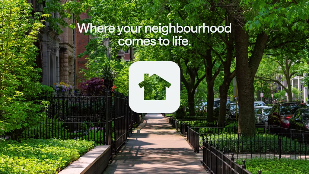 Sunny, tree-lined city sidewalk with fences and gardens. Text: “Where your neighbourhood comes to life.” White house icon below.