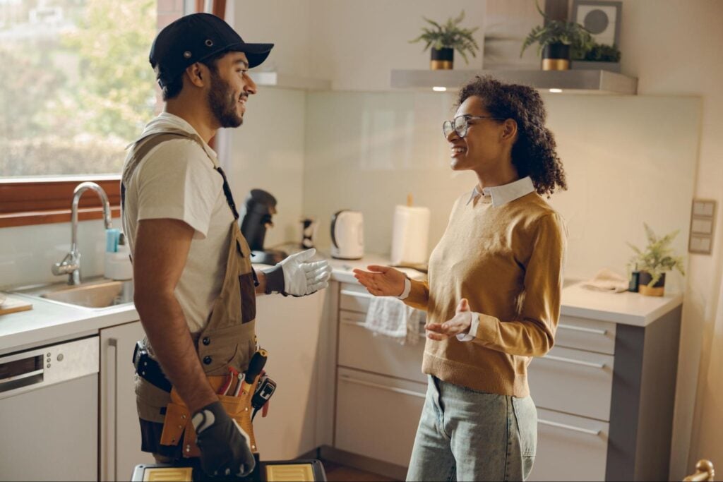 A contractor discusses project details with a homeowner in a modern kitchen, showcasing Hook Agency's client-focused approach.