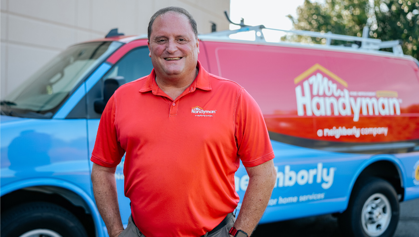 Contractor in Mr. Handyman uniform smiles by branded van, illustrating how local SEO drives business growth for contractors.