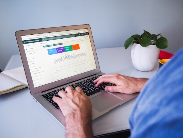 Google Search Console analytics on a laptop—essential data for home service businesses. Desk includes plant and closed notebook.