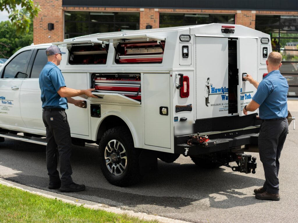 Two workers in blue uniforms use tools by a white utility truck with open compartments, highlighting local vs. Google Ads impact.