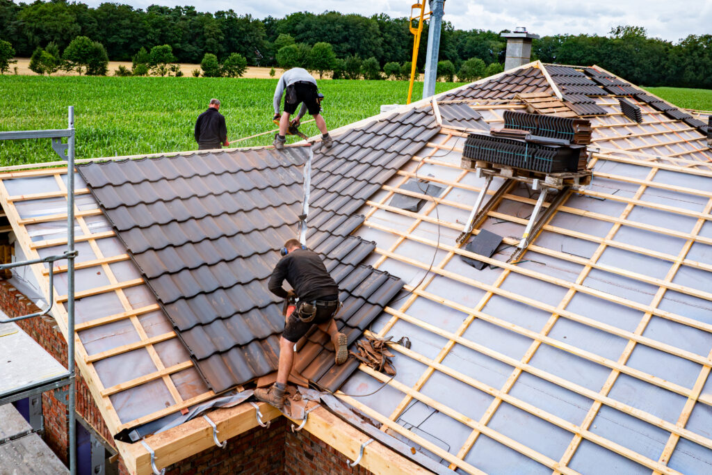 Workers install roof tiles on a home under construction; share progress photos like this to build trust on social media.