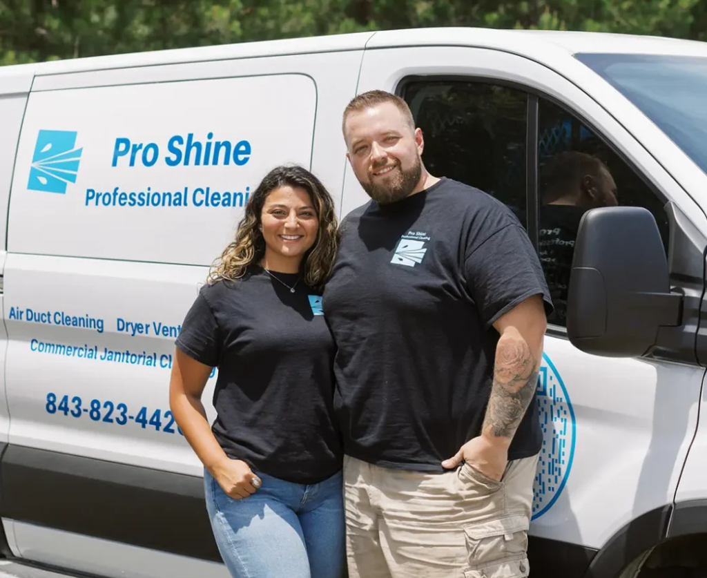 Two team members in black Pro Shine shirts stand in front of a branded white Pro Shine Professional Cleaning van. The van, parked outdoors, clearly lists air duct cleaning services and displays the company’s contact phone number, emphasizing their air duct expertise.