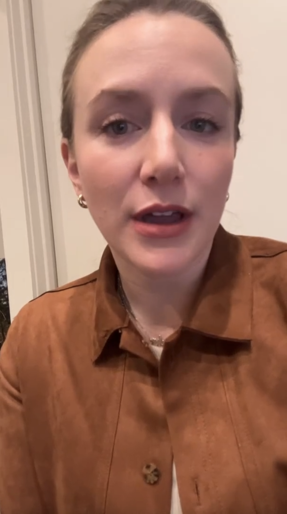 Professional portrait of a woman with light skin and light brown, pulled-back hair, wearing a brown jacket and small earrings. She faces the camera in a neutral indoor setting—featured on Hook Agency's website.