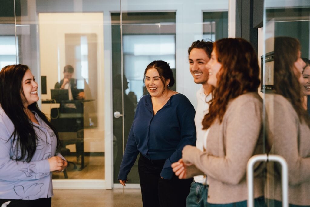 Four people collaborate in a modern glass-walled office, evaluating a marketing agency.