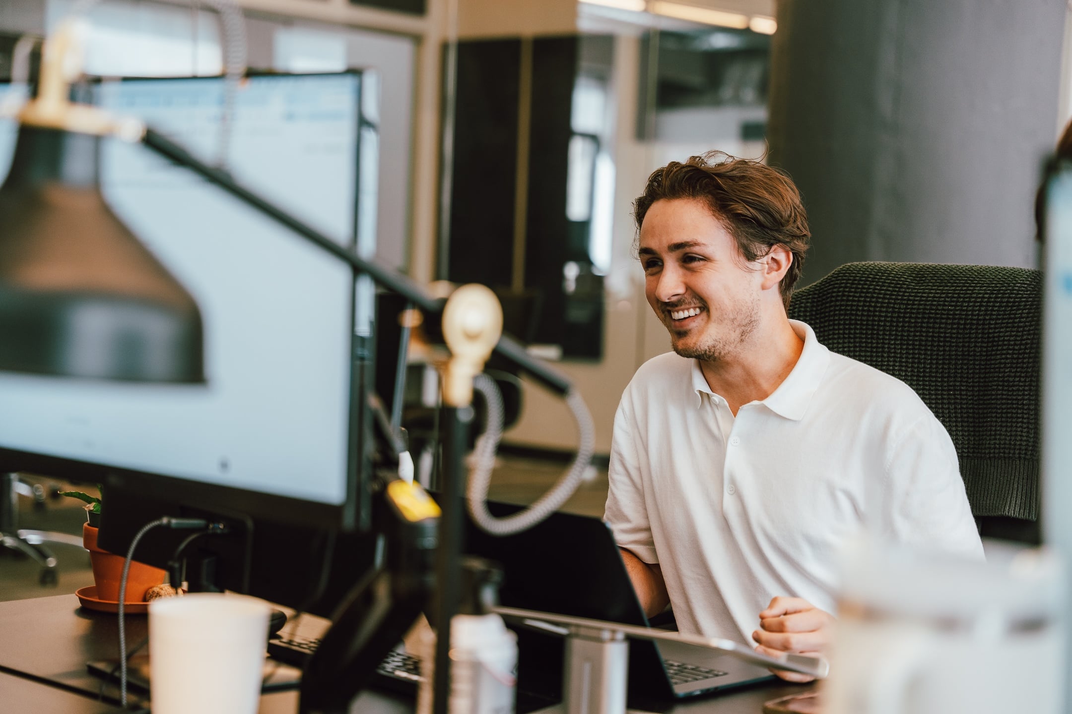 A professional in a white polo shirt manages paid ads at a computer in the Hook Agency office.